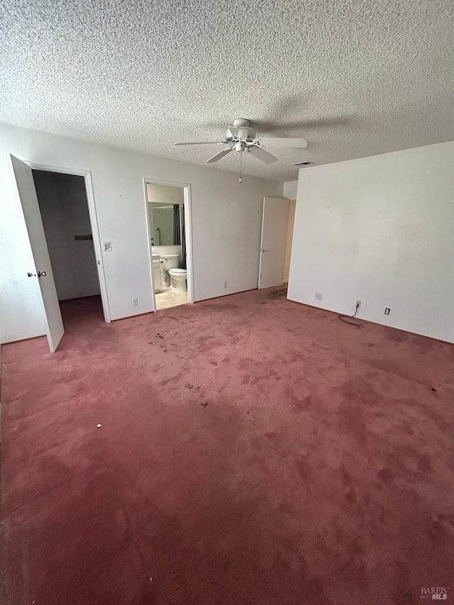 interior space featuring a walk in closet, carpet floors, and a textured ceiling