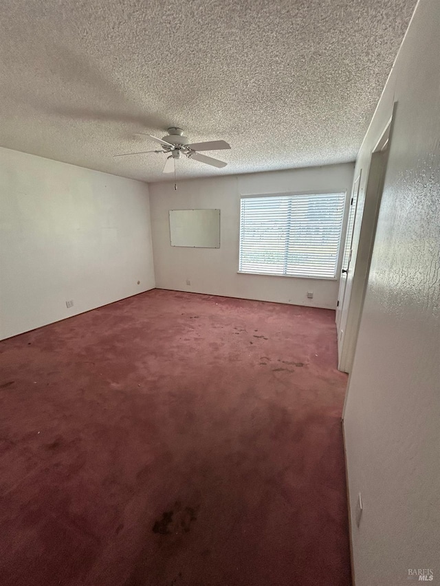 empty room with a ceiling fan, a textured ceiling, and carpet