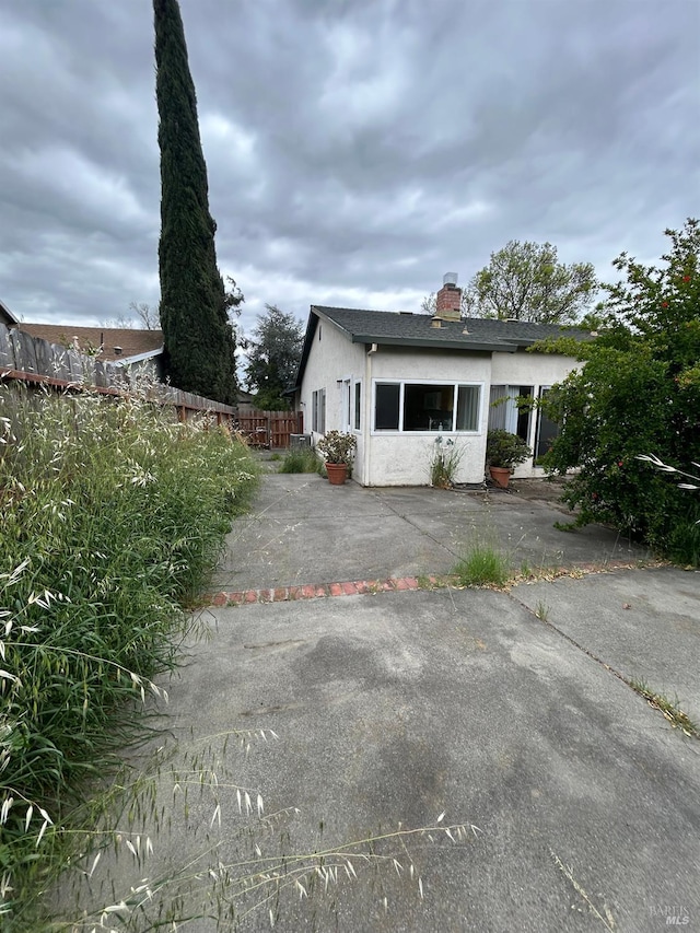 exterior space with fence, a chimney, and stucco siding