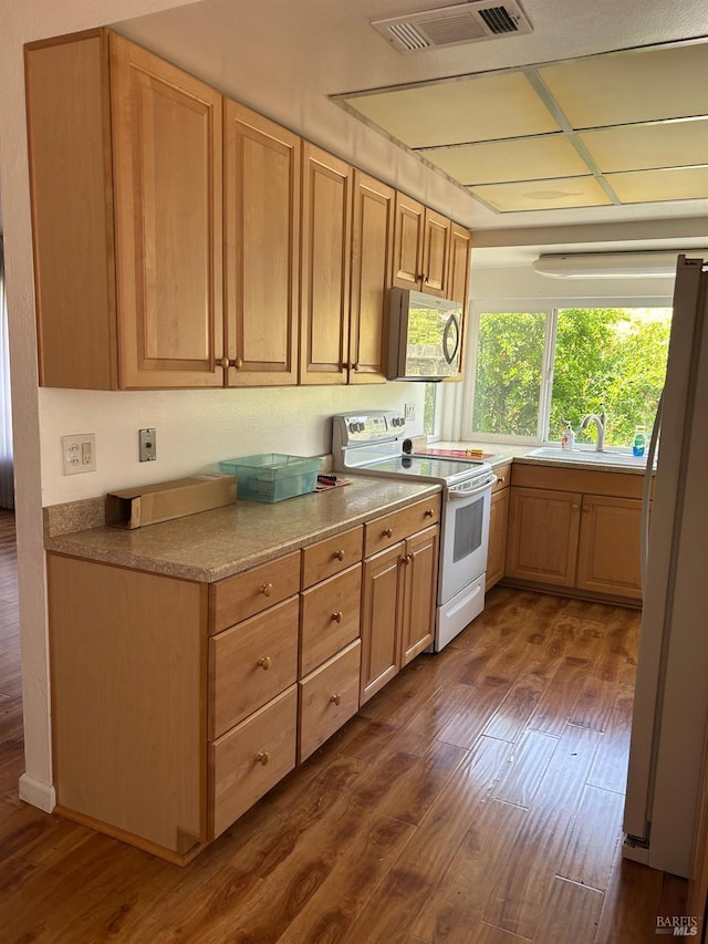 kitchen with a sink, dark wood-style floors, visible vents, and white appliances