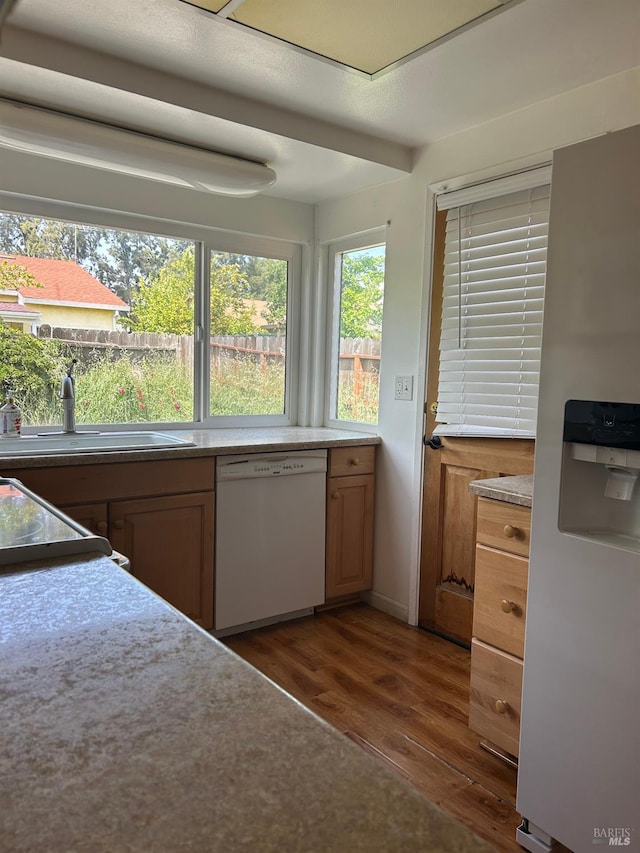 kitchen with stainless steel fridge with ice dispenser, light countertops, dishwasher, dark wood-style flooring, and a sink