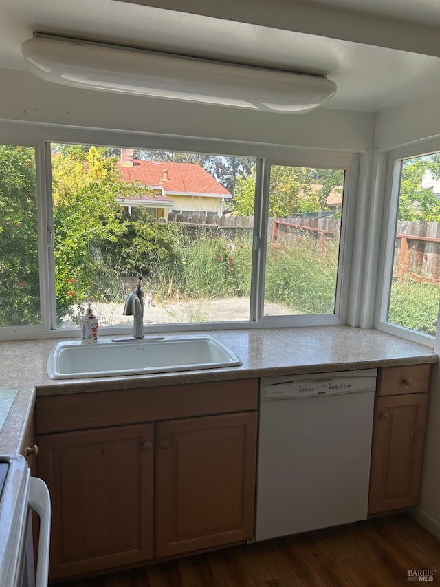 kitchen with a sink, dark wood-style flooring, stove, light countertops, and dishwasher