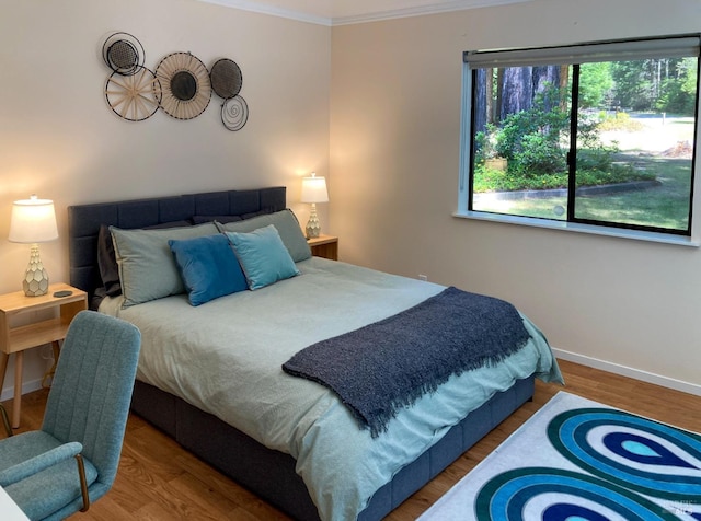 bedroom featuring baseboards, ornamental molding, and wood finished floors