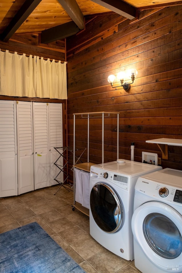 washroom with tile patterned flooring, wooden ceiling, washing machine and clothes dryer, and wood walls