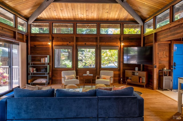 living room with wooden walls, vaulted ceiling with beams, and wood ceiling