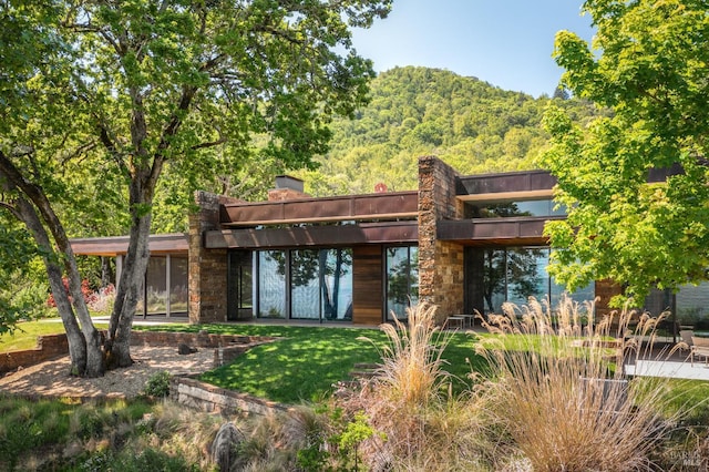 back of property with a wooded view and a yard