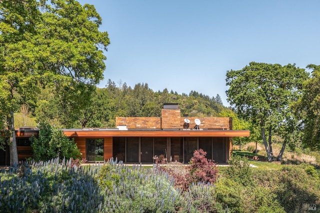 rear view of house with a sunroom and a chimney