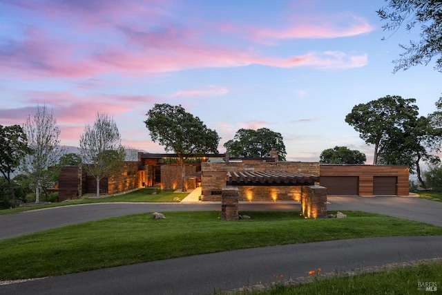 contemporary house featuring a lawn, stone siding, and aphalt driveway