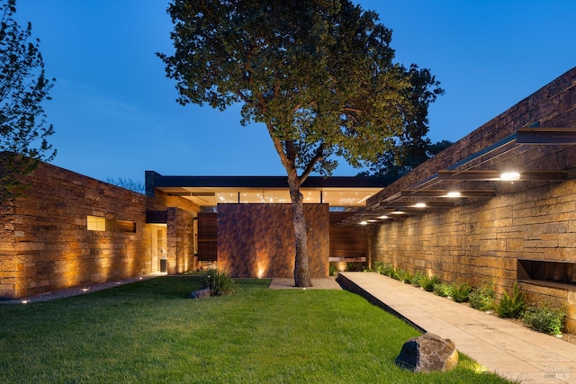back of property with a yard and stone siding