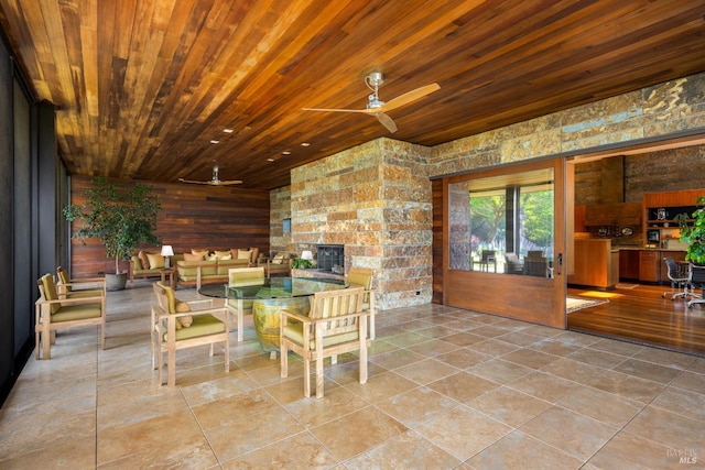 tiled dining area featuring ceiling fan, a stone fireplace, and wood ceiling