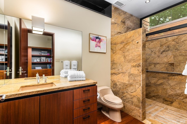 full bathroom featuring wood finished floors, walk in shower, toilet, vanity, and visible vents
