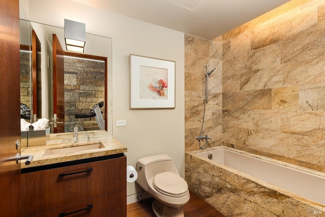 full bathroom with toilet, wood finished floors, vanity, and tiled shower / bath combo