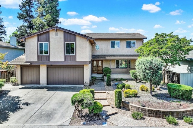 view of front facade with concrete driveway, stucco siding, fence, a porch, and a garage
