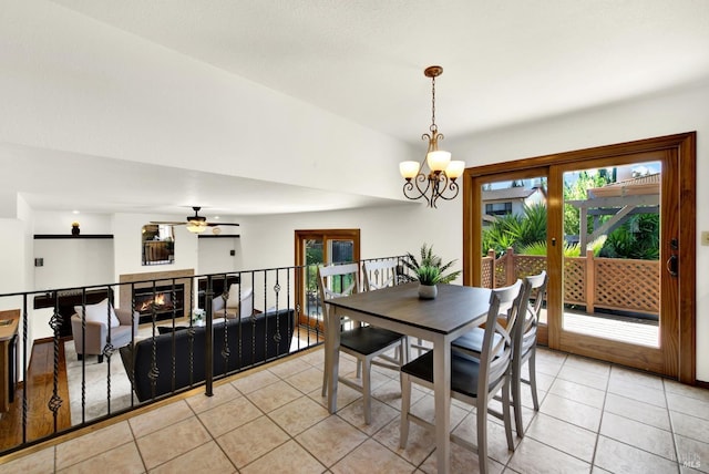 dining area featuring light tile patterned floors, a healthy amount of sunlight, and ceiling fan with notable chandelier