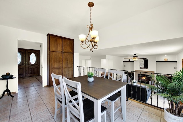 dining space with baseboards, ceiling fan with notable chandelier, and light tile patterned flooring
