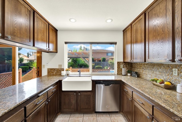 kitchen with dishwasher, a sink, light tile patterned flooring, tasteful backsplash, and stone countertops