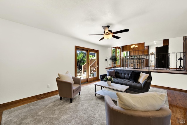 living room featuring baseboards, wood finished floors, and ceiling fan with notable chandelier