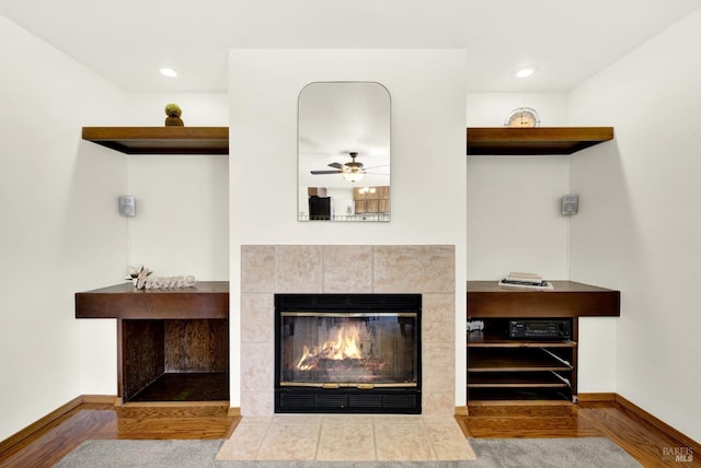 details featuring wood finished floors, ceiling fan, a tiled fireplace, and baseboards