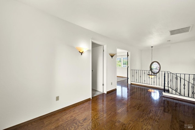 unfurnished room with baseboards, visible vents, and wood finished floors