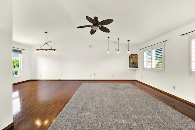 empty room with lofted ceiling, ceiling fan, visible vents, baseboards, and dark wood-type flooring