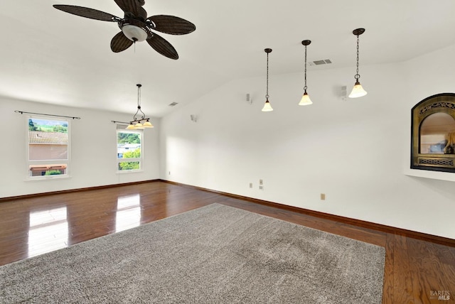 spare room with lofted ceiling, visible vents, wood finished floors, and baseboards