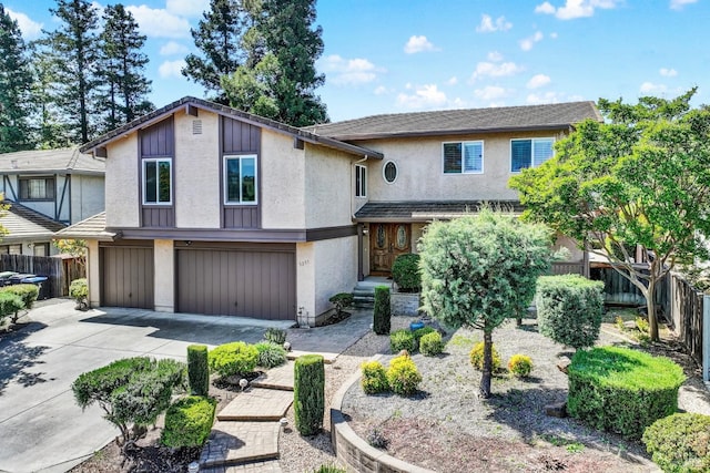 view of front facade featuring fence, concrete driveway, stucco siding, and a garage