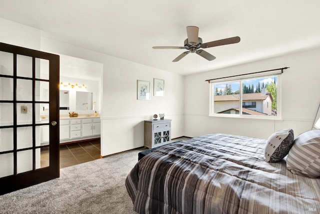bedroom with dark colored carpet, a ceiling fan, ensuite bath, and dark tile patterned flooring