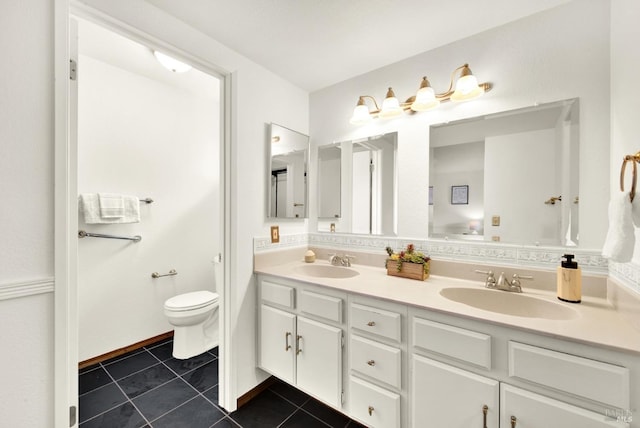 bathroom featuring toilet, double vanity, a sink, and tile patterned floors