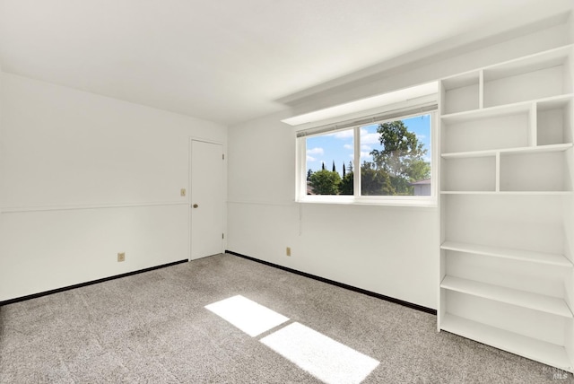 carpeted empty room featuring baseboards