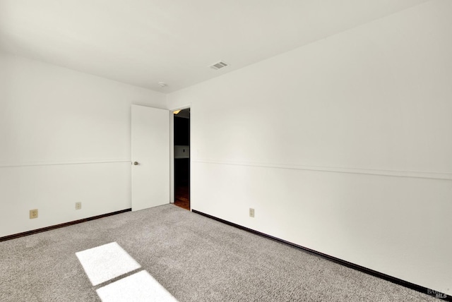 carpeted spare room featuring baseboards and visible vents