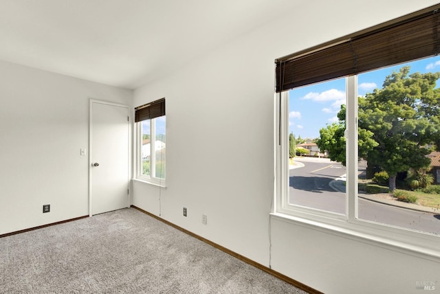 carpeted empty room featuring baseboards