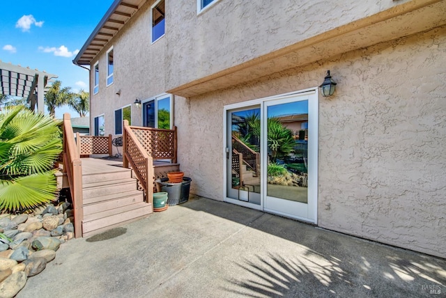 view of exterior entry featuring stucco siding and a patio area