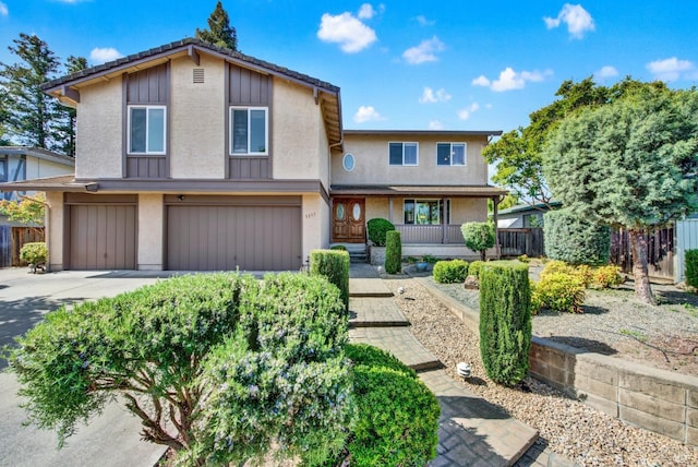view of front of home with a porch, stucco siding, fence, a garage, and driveway