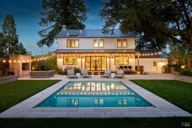 back of property with a standing seam roof, metal roof, a yard, and a patio