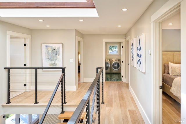 corridor featuring recessed lighting, light wood-style flooring, independent washer and dryer, an upstairs landing, and baseboards