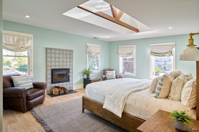 bedroom featuring a tile fireplace, wood finished floors, recessed lighting, and visible vents