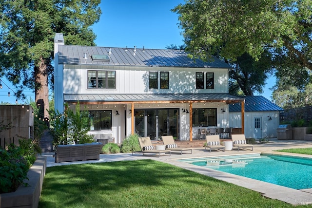 rear view of house with metal roof, a standing seam roof, a patio, and an outdoor pool
