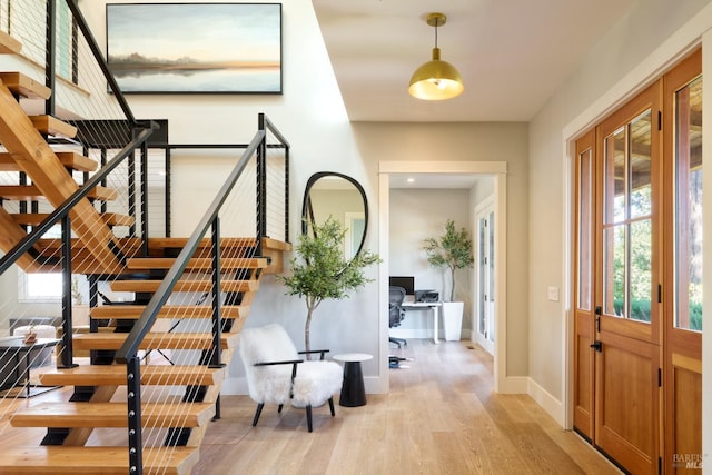 entrance foyer with baseboards, light wood-type flooring, and stairs