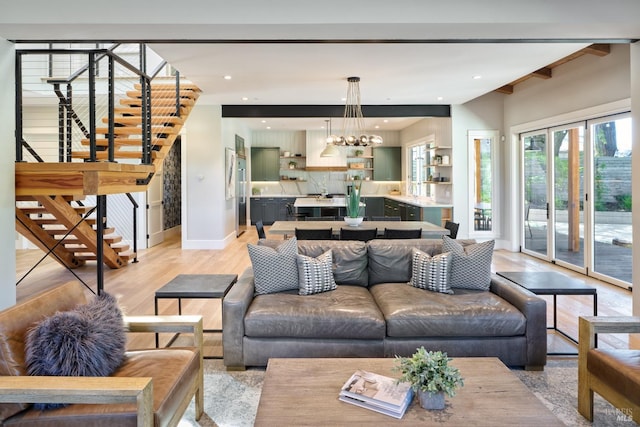 living room with light wood finished floors, recessed lighting, stairway, a chandelier, and baseboards