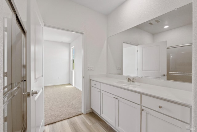 bathroom featuring wood finished floors, vanity, visible vents, and baseboards