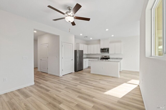 kitchen featuring appliances with stainless steel finishes, light countertops, white cabinets, ceiling fan, and light wood finished floors