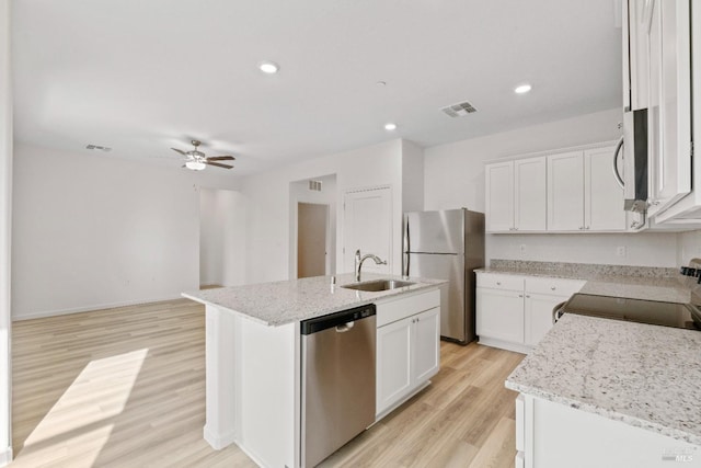 kitchen with a kitchen island with sink, stainless steel appliances, light wood finished floors, a sink, and a ceiling fan