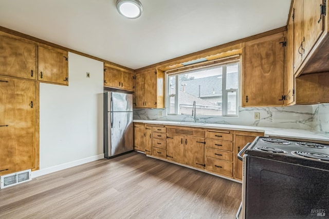 kitchen featuring visible vents, range with electric stovetop, light countertops, and freestanding refrigerator