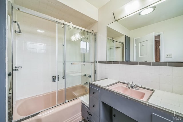 bathroom featuring combined bath / shower with glass door, vanity, and backsplash