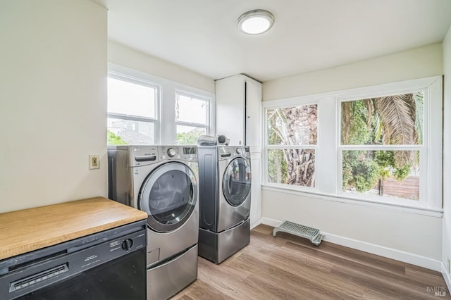 laundry room featuring baseboards, a wealth of natural light, light wood-style floors, and washing machine and dryer