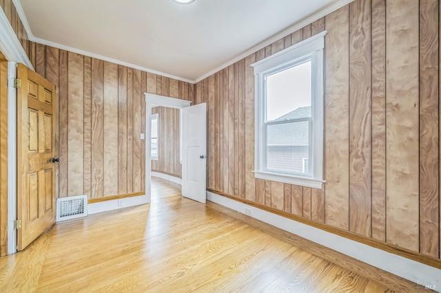 spare room featuring crown molding, visible vents, wood finished floors, and baseboards