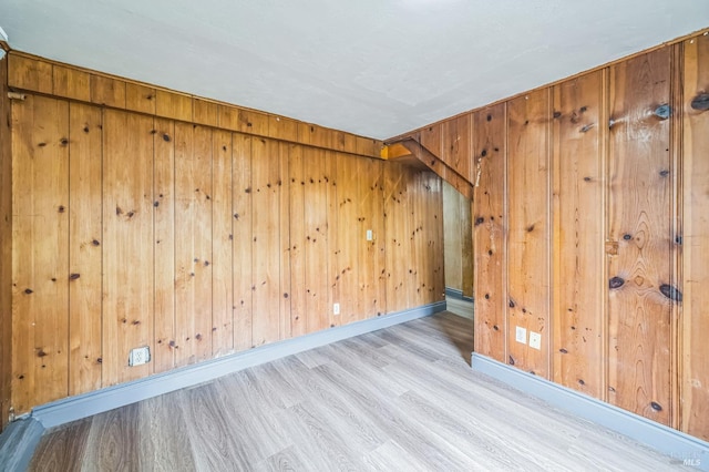 additional living space with baseboards, wood finished floors, and wooden walls