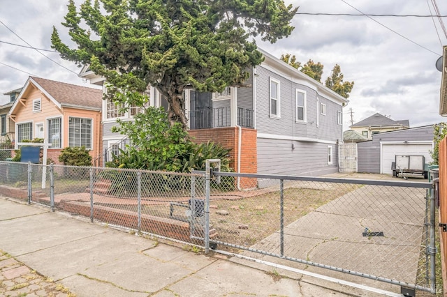 view of front of property with a gate, brick siding, fence private yard, and an outdoor structure
