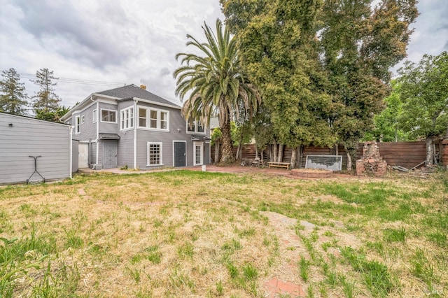 rear view of house with a lawn and fence