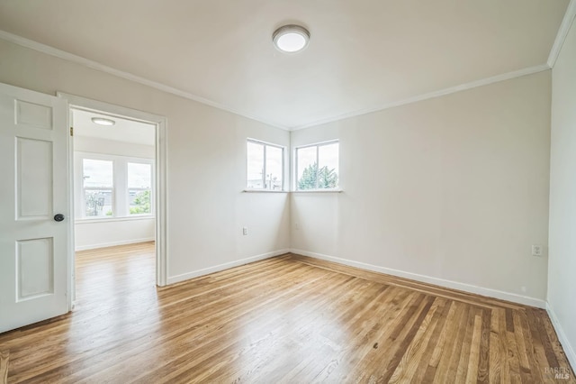 empty room with ornamental molding, baseboards, and light wood-type flooring